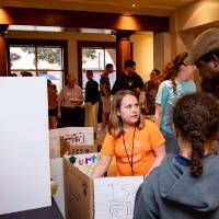 parent engaging with student presenters at their exhibit table